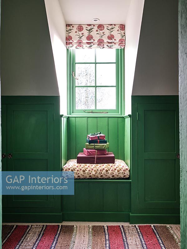 Cadeaux emballés sur petit siège de fenêtre avec des murs lambrissés peints en vert