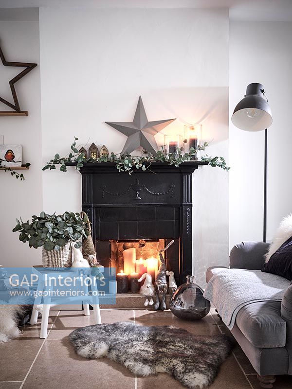 Bougies allumées dans une cheminée noire décorée pour Noël