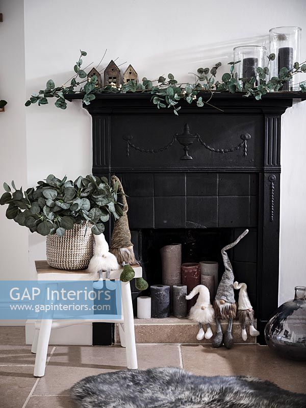 Bougies allumées dans une cheminée noire décorée pour Noël