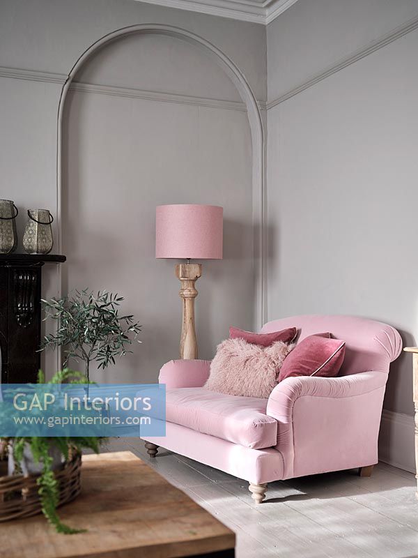 Canapé et lampadaire rose à côté d'un mur peint en gris