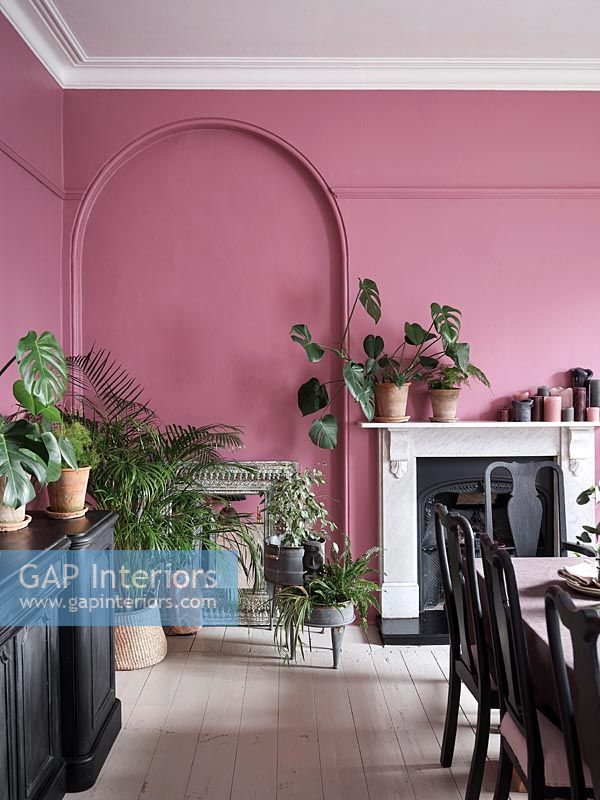 Salle à manger moderne avec des murs peints en rose et des meubles noirs