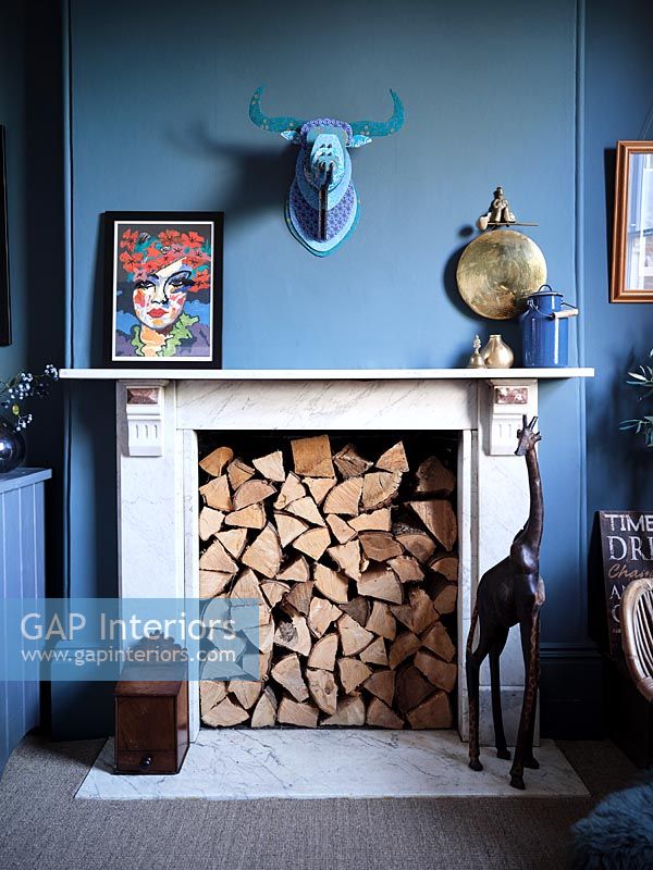 Cheminée remplie de bûches dans le salon peint en bleu moderne