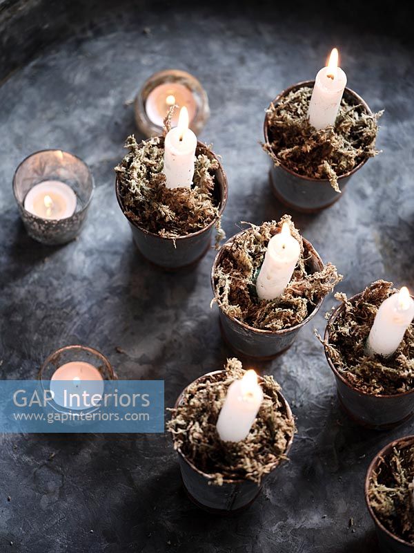 Bougies allumées dans de petits pots avec de la mousse décorative