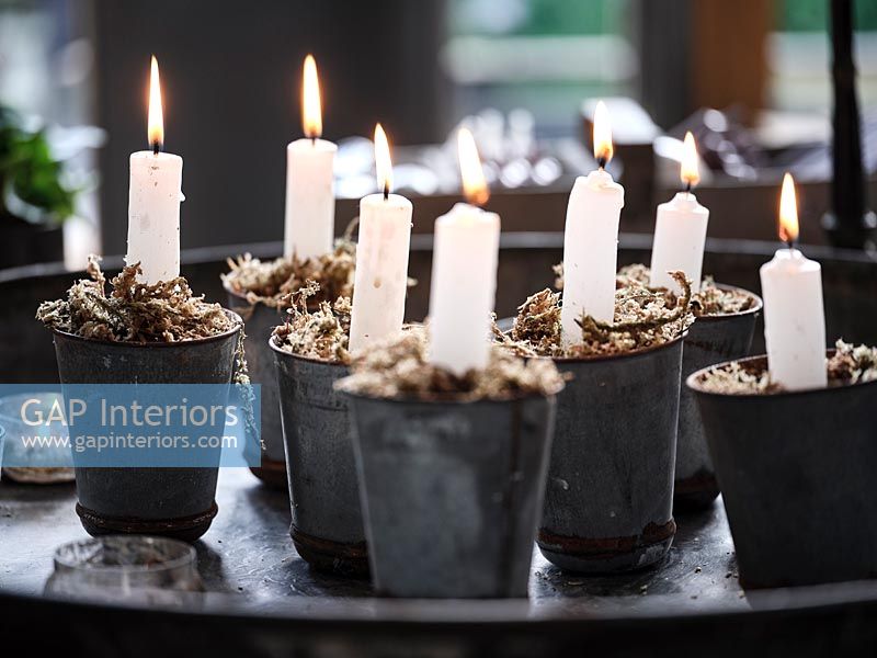 Bougies allumées dans de petits pots avec de la mousse décorative