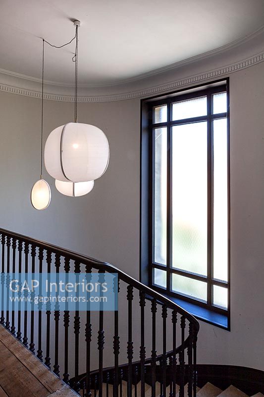 Luminaire suspendu blanc au-dessus de l'escalier peint en noir et blanc