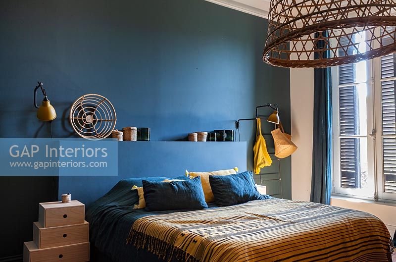 Murs peints en bleu foncé et tête de lit dans une chambre moderne