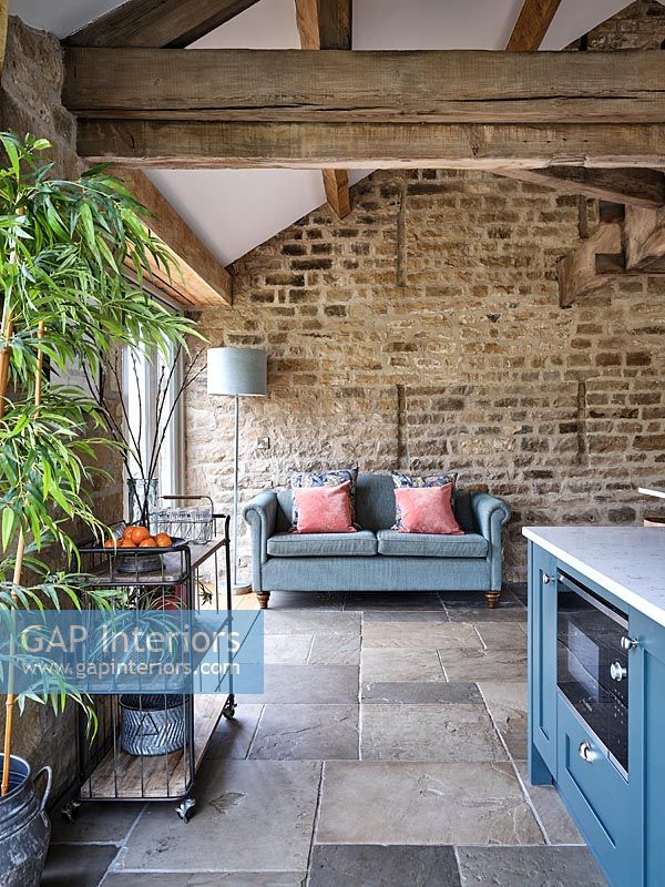 Canapé à côté de mur en pierres apparentes dans la cuisine de campagne moderne