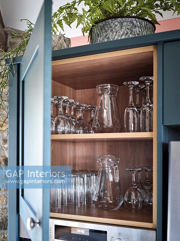 Ouvrez la porte de l'armoire de cuisine avec des étagères de verres