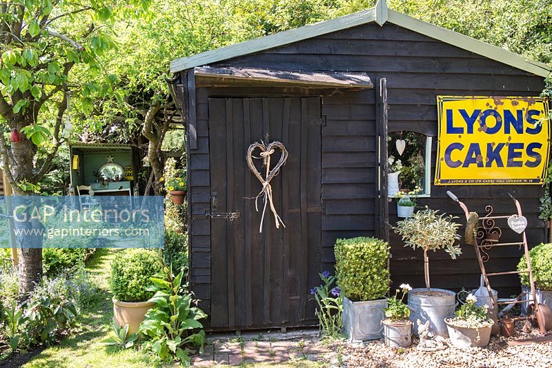 Hangar peint en noir avec vintage shop sign in cottage garden