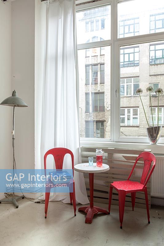 Chaises rouge vif et petite table d'appoint à côté de la fenêtre