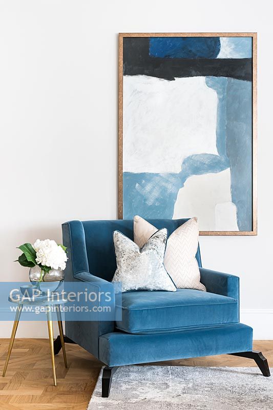 Fauteuil moderne bleu avec une grande peinture sur le mur derrière
