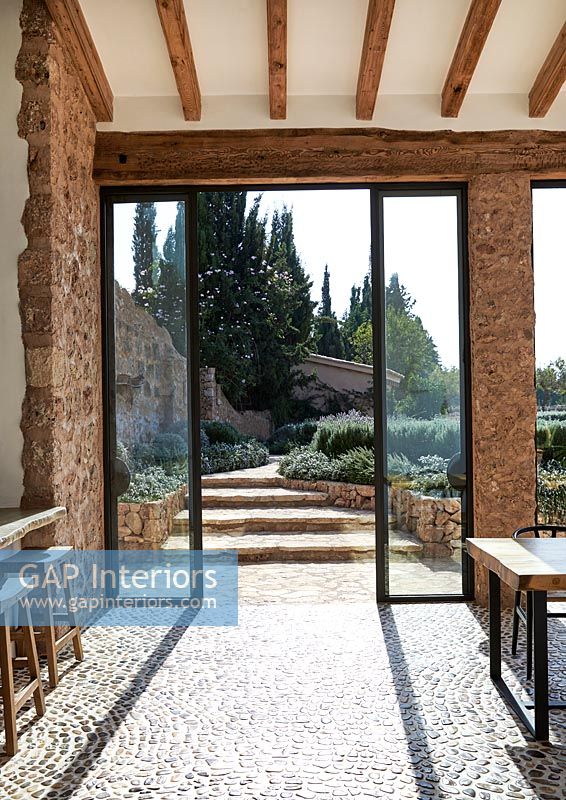 Salle à manger moderne avec sol en galets texturés avec vue sur le jardin