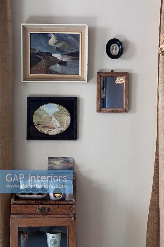 Affichage d'images encadrées sur le mur au-dessus de la petite armoire en bois