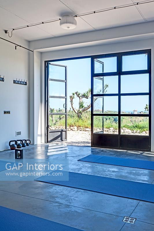 Studio de yoga moderne avec vue panoramique à travers les portes-fenêtres ouvertes