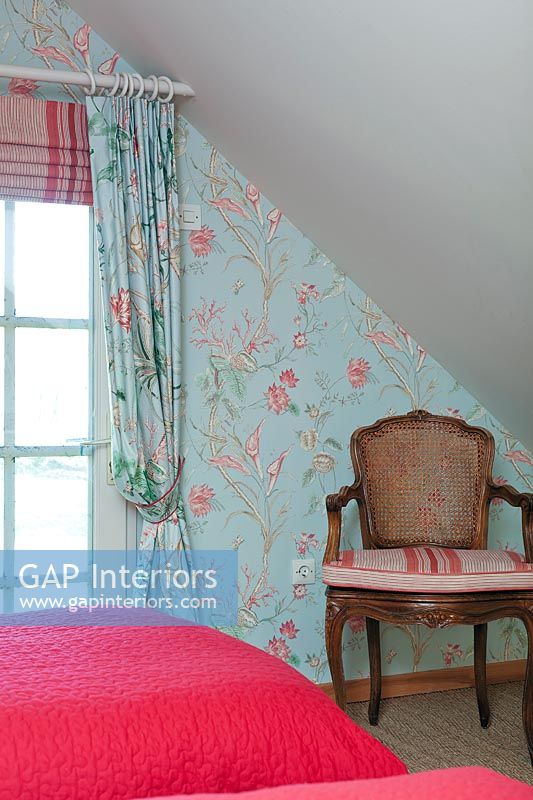 Fauteuil en bois contre mur tapissé floral coloré dans la chambre