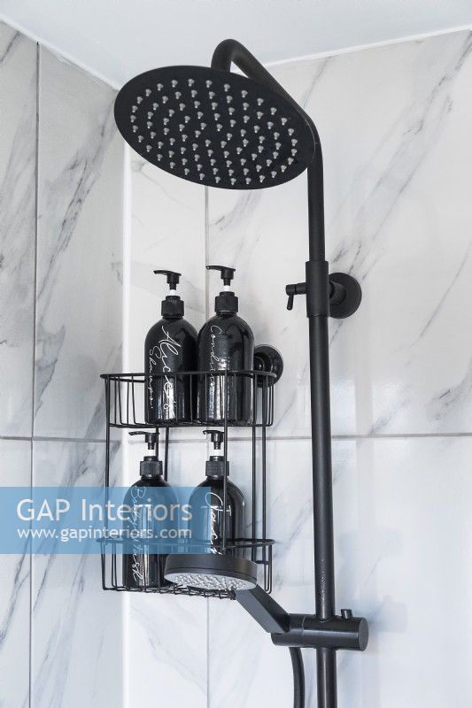 Détail de la pomme de douche noire et des carreaux de marbre gris dans la salle de bains moderne