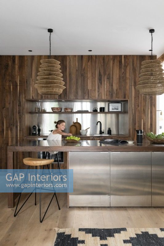 Fille dans une cuisine moderne ouverte avec armoire intégrée en bois et acier inoxydable