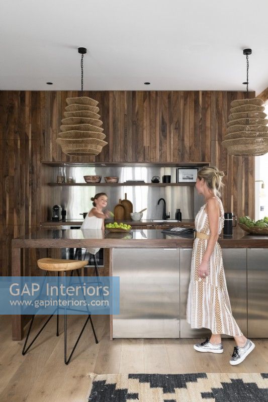 Famille dans une cuisine moderne à aire ouverte avec armoire intégrée en bois et acier inoxydable