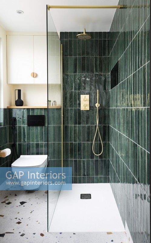 Salle de bain moderne et contemporaine avec carreaux verticaux vert, carreaux de sol en terrazzo et raccords en laiton, robinets