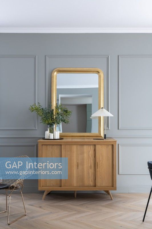 Cabinet en bois moderne et miroir encadré d'or contre le mur gris