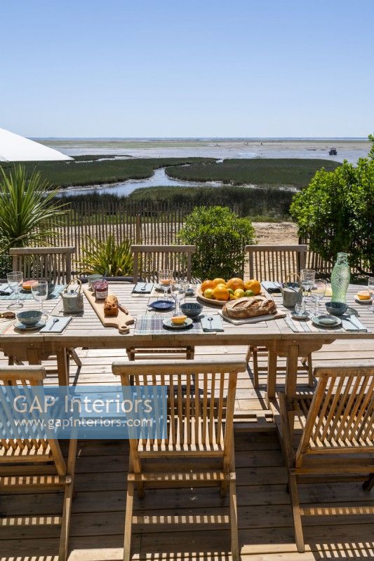 Table à manger extérieure dressée pour le déjeuner avec vue sur la côte en été