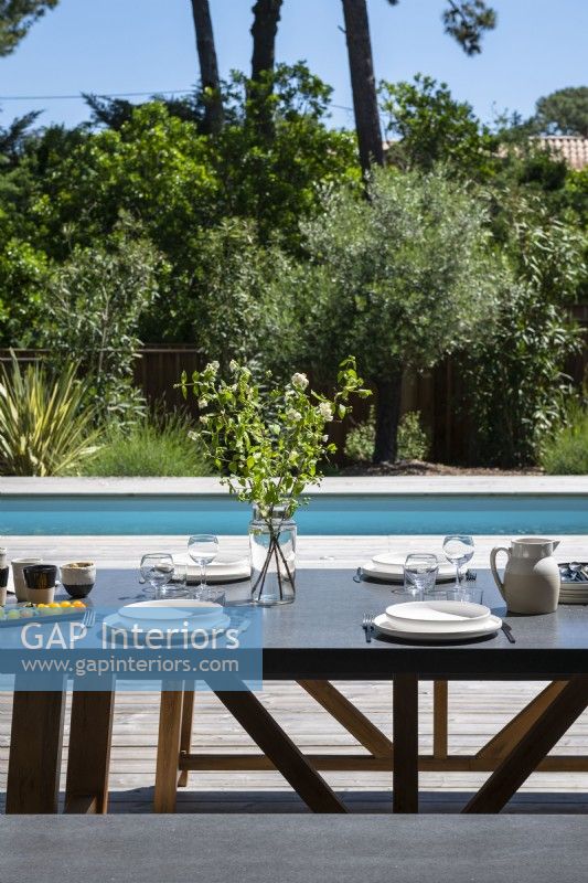 Table à manger extérieure posée pour le déjeuner sur la terrasse à côté de la piscine