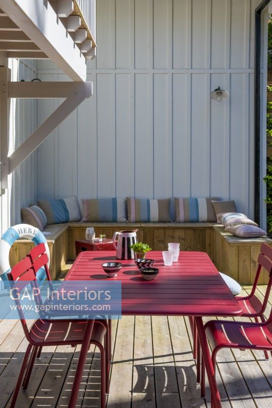 Table à manger rouge et chaises sur terrasse avec banquette intégrée