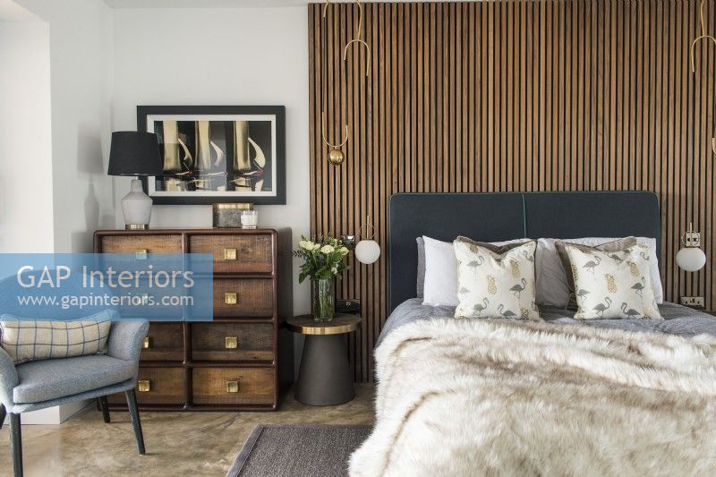 Chambre à coucher moderne avec mur à lattes en bois derrière le lit