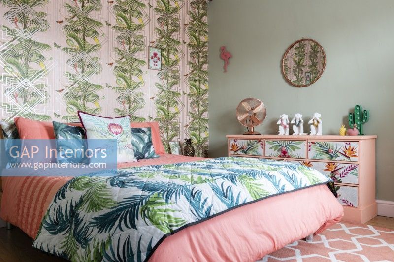 Chambre à coucher moderne avec papier peint et couvre-lit à motifs de palmiers et commode peinte à fleurs