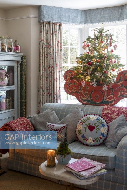 Salon avec canapé confortable et rideaux fleuris, décoré pour Noël