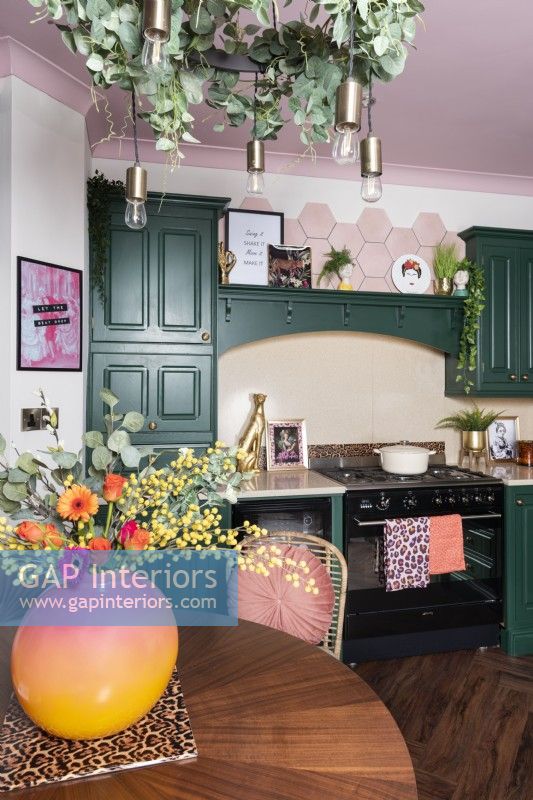 Cuisine avec gamme et armoires peintes en vert et plafond rose
