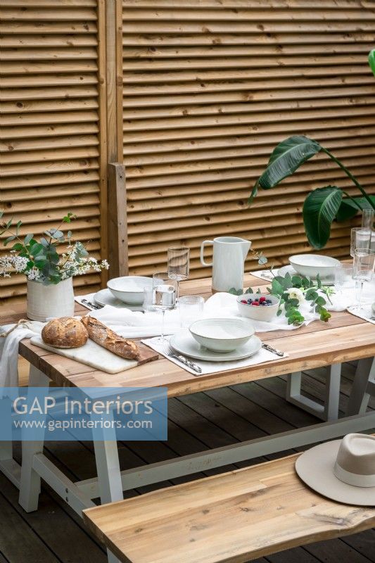 Table de style pique-nique dressée pour le déjeuner à côté d'une clôture en bois