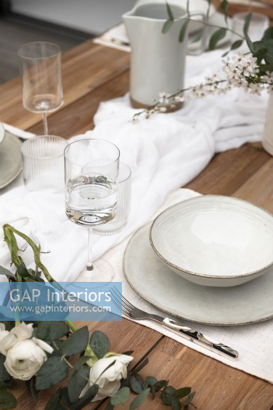 Vaisselle blanche sur table à manger extérieure en bois - détail