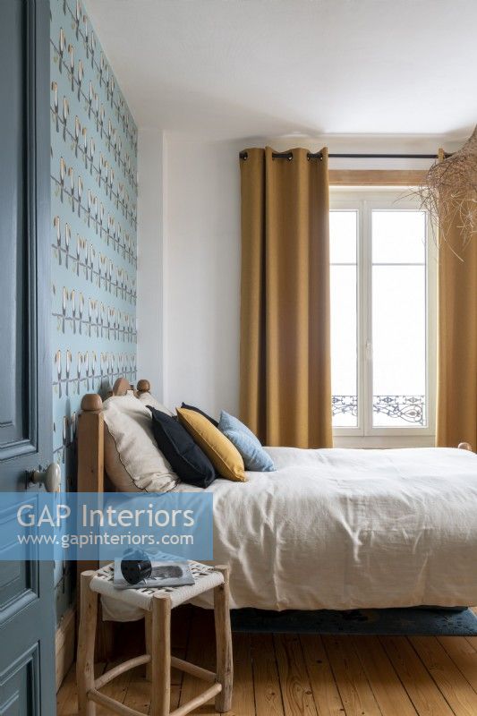 Chambre à coucher moderne avec papier peint à motifs bleus et rideaux moutarde