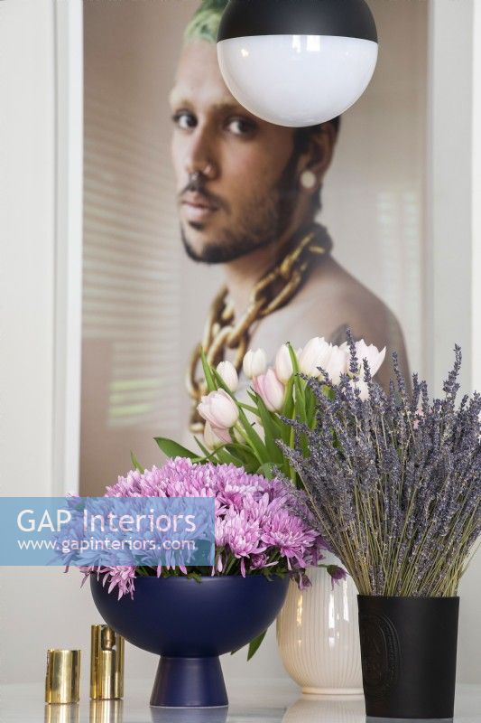 Affichage de fleurs dans des vases avec une grande photographie d'un homme en arrière-plan.