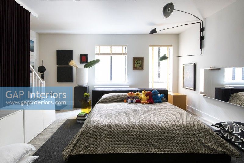 Chambre à coucher moderne avec des expositions d'œuvres d'art et une collection d'animaux en peluche de Sesame Street sur le lit.