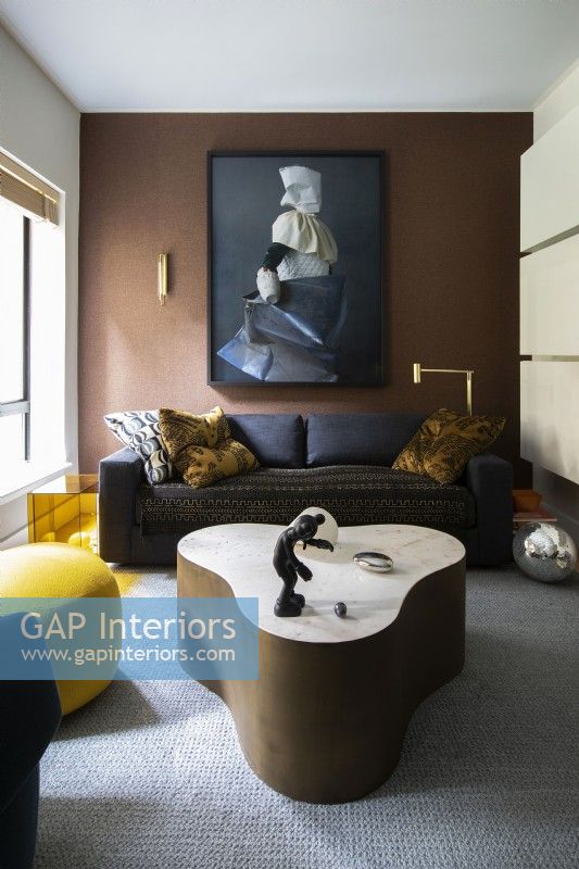 Salon moderne aux couleurs bleu foncé et marron avec table basse vintage en marbre et laiton.