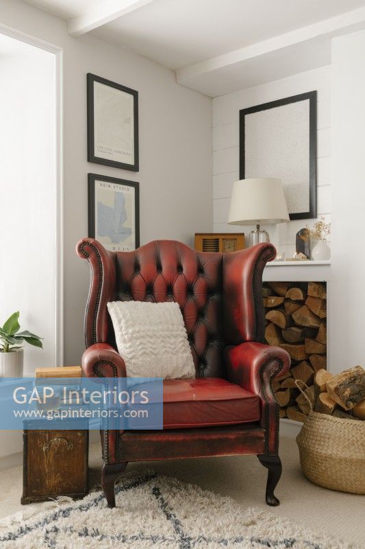 Salon contemporain à aire ouverte dans un cottage de Cornouailles. Doté d'un poêle à bois et d'un fauteuil à oreilles en cuir rouge.