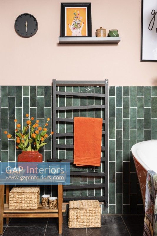 Radiateur sèche-serviettes noir dans une salle de bains carrelée de vert