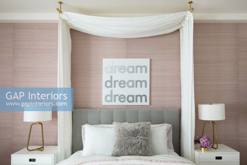Chambre féminine en rose et blanc avec un auvent à rideaux au-dessus du lit.