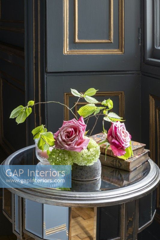 Roses anciennes, feuilles de hêtre et hortensia dans un vase dans une chambre lambrissée