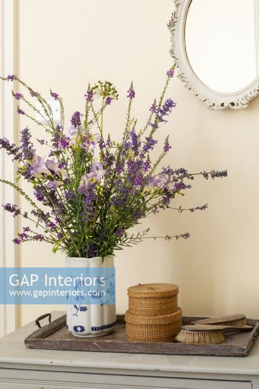 Vase de fleurs de style champêtre informel sur une commode, ensemble de pinceaux vintage et petits paniers