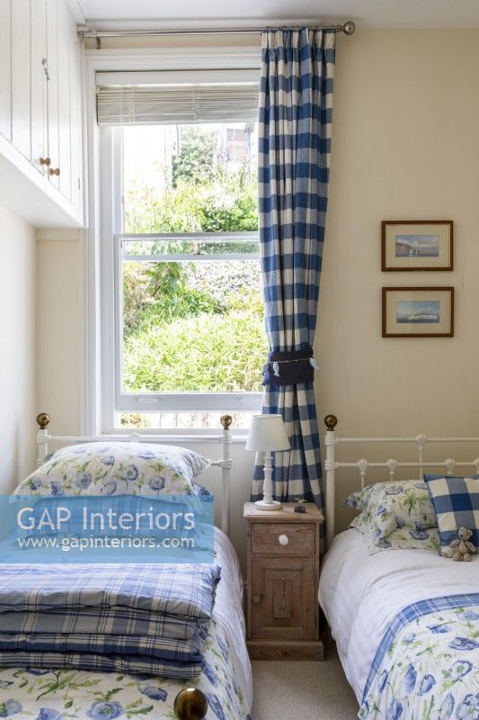 Chambre à deux lits avec de jolis tissus de ferme en bleu et blanc, des têtes de lit en laiton