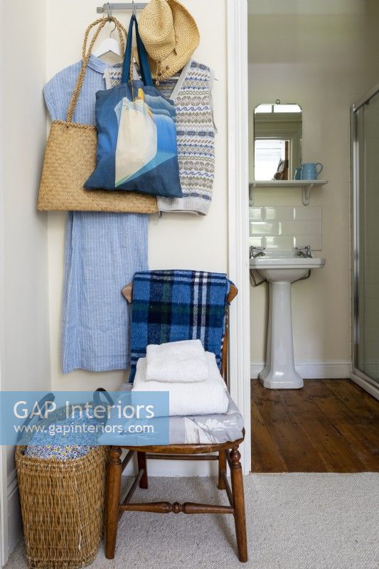 Chaise en bois dans la chambre, tissus rustiques simples et vue sur la salle de bain attenante