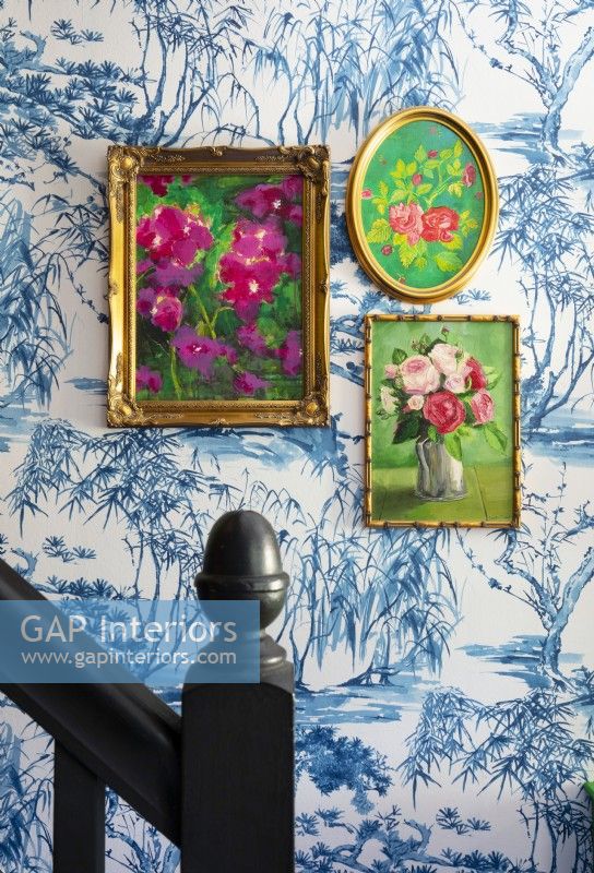 Peintures florales encadrées sur mur tapissé - détail du couloir
