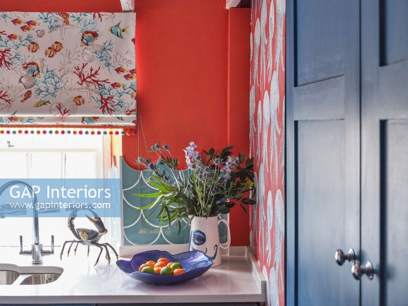Vase d'inspiration côtière, bol et ornement de crabe sur le comptoir de la cuisine dans une cuisine colorée