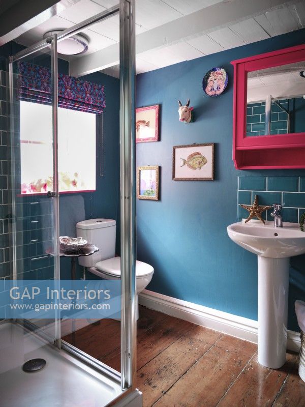 Salle de bain bleue avec œuvres d'art et miroir rose