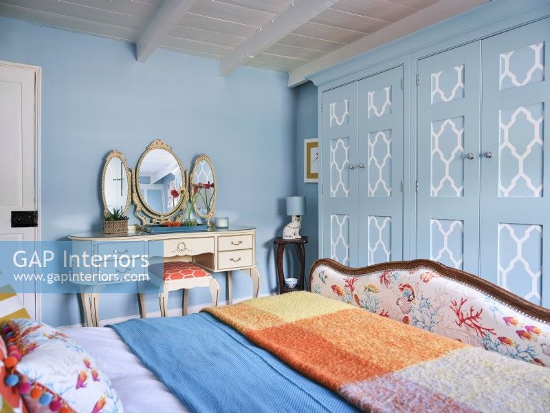 Lit capitonné vintage avec coiffeuse dorée dans une chambre à motifs bleus