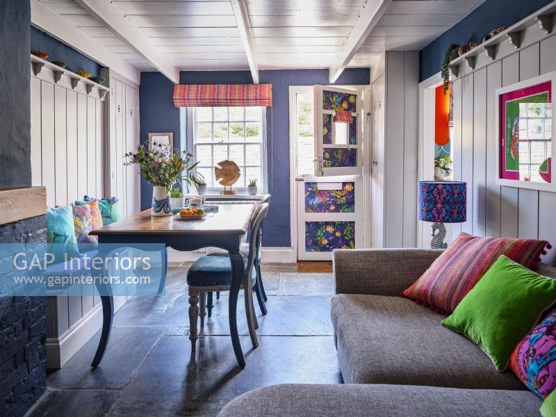 Salon et salle à manger décloisonnés avec des murs lambrissés bleus et blancs et un ensemble de table vintage
