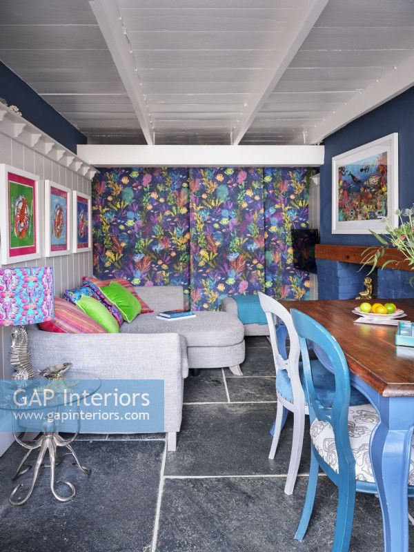 Salle à manger ouverte et colorée avec un mur à motifs et des œuvres d'art marines